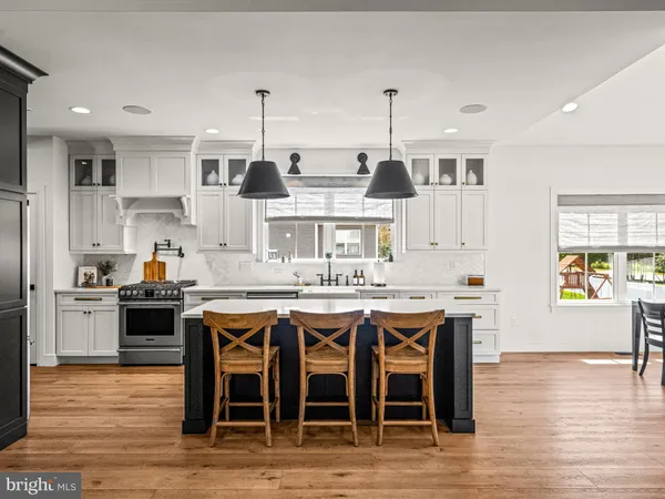 a kitchen with stainless steel appliances granite countertop a stove top oven a sink dishwasher and white cabinets with wooden floor