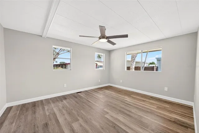 a view of empty room with wooden floor and fan