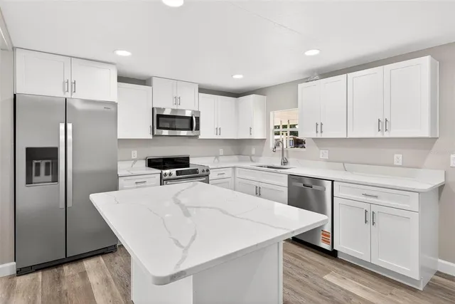 a kitchen with granite countertop white cabinets and stainless steel appliances