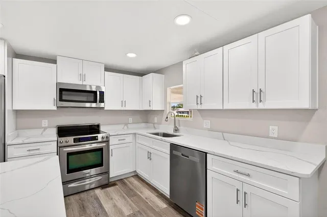 a kitchen with granite countertop white cabinets and stainless steel appliances