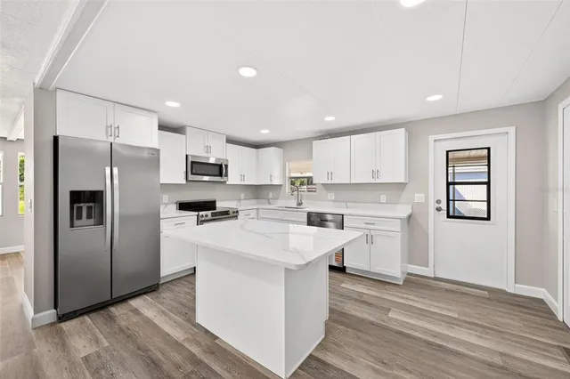 a kitchen with stainless steel appliances granite countertop a refrigerator sink and white cabinets