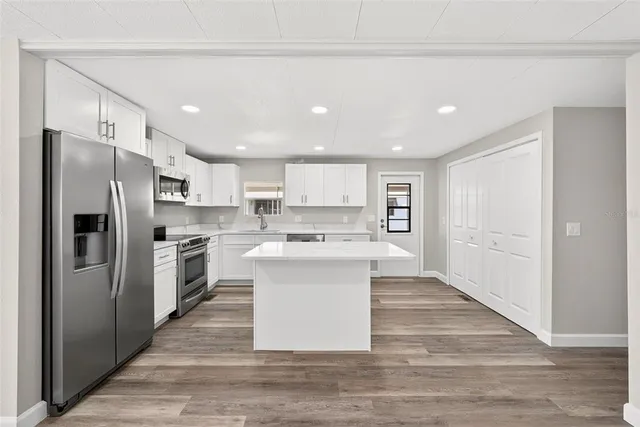 a large kitchen with stainless steel appliances a sink and refrigerator