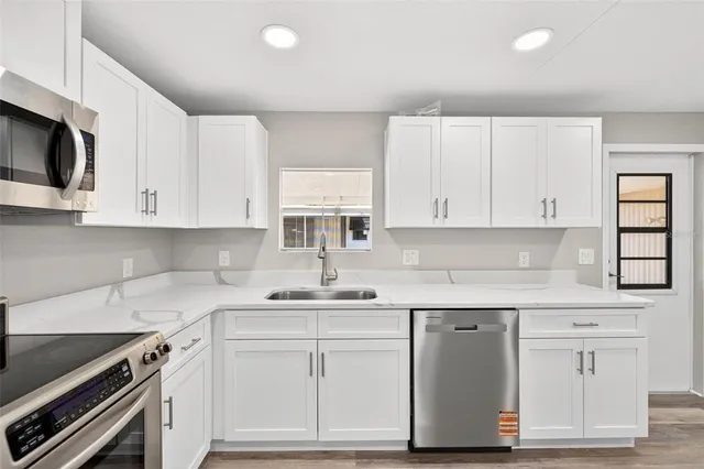 a kitchen with white cabinets stainless steel appliances and sink