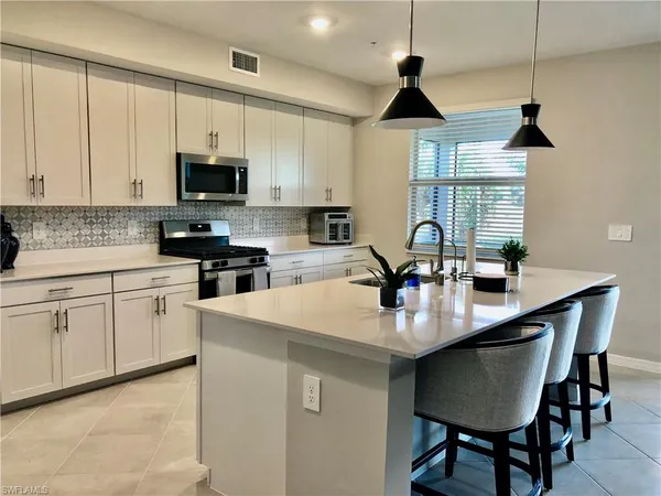 a kitchen with appliances a sink a counter and chairs