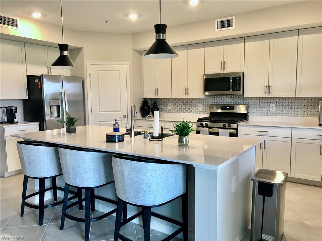 43253 Water Bird Way, Unit 5811 Babcock Ranch, FL 33982 - Photo 5 of 21 a kitchen with stainless steel appliances a sink a stove a refrigerator and cabinets