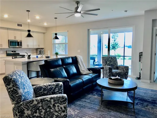 a living room with furniture kitchen view and a large window