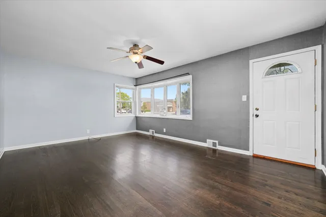 a view of an empty room with a window and wooden floor