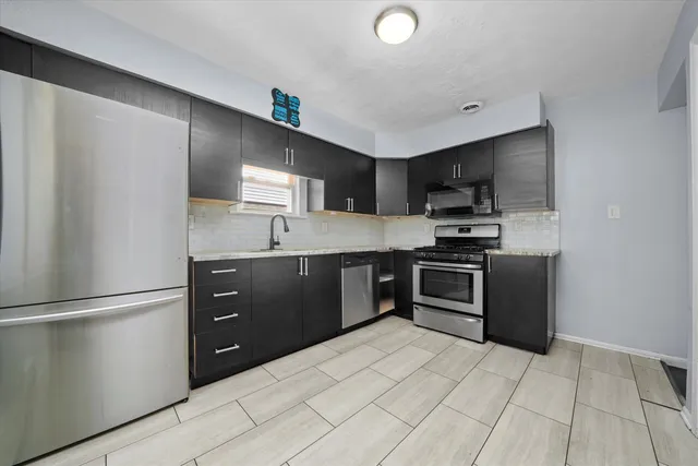 a kitchen with granite countertop a refrigerator and a stove top oven