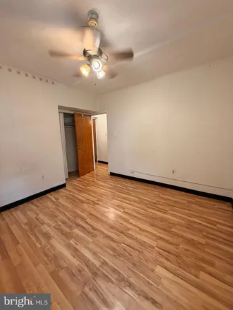 an empty room with wooden floor and fan