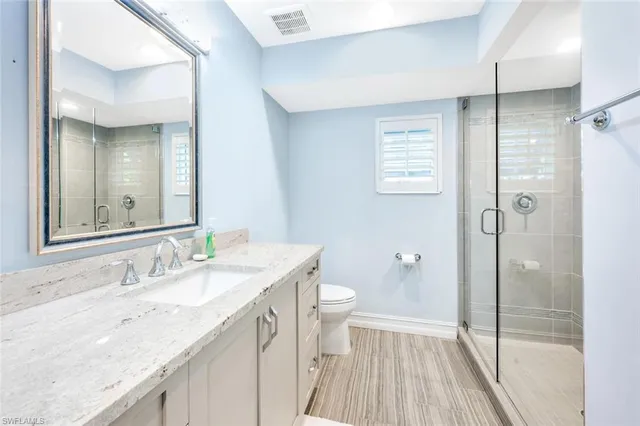 a bathroom with a granite countertop sink a toilet and shower