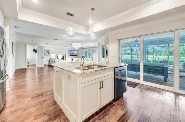 a large white kitchen with wooden floor and a window