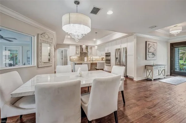 a large dining room with wooden floor a chandelier a wooden table and chairs