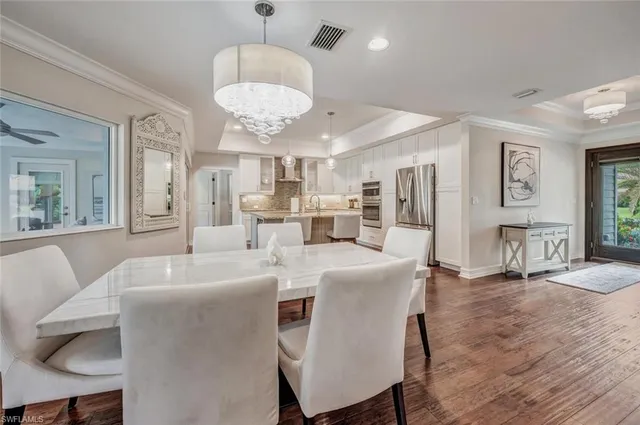 a large dining room with wooden floor a chandelier a wooden table and chairs