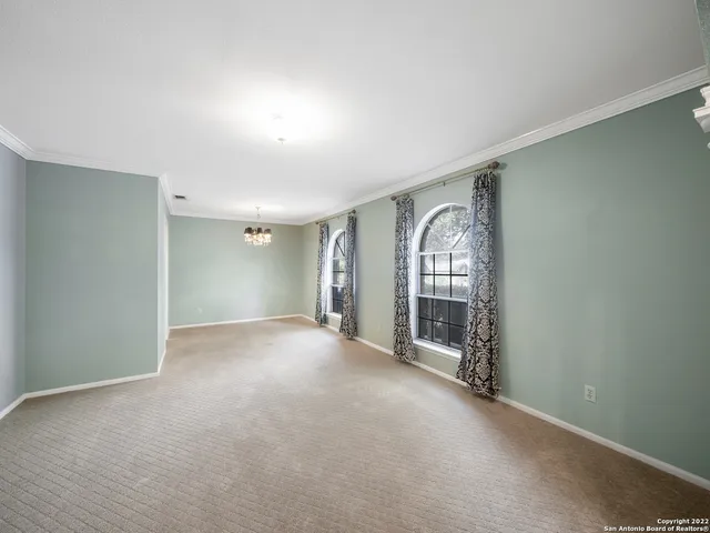 a view of an empty room with wooden floor and windows