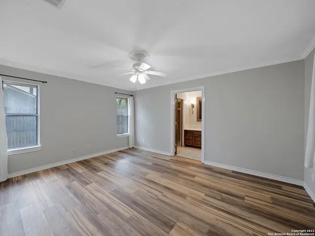 a view of an empty room with window and chandelier fan