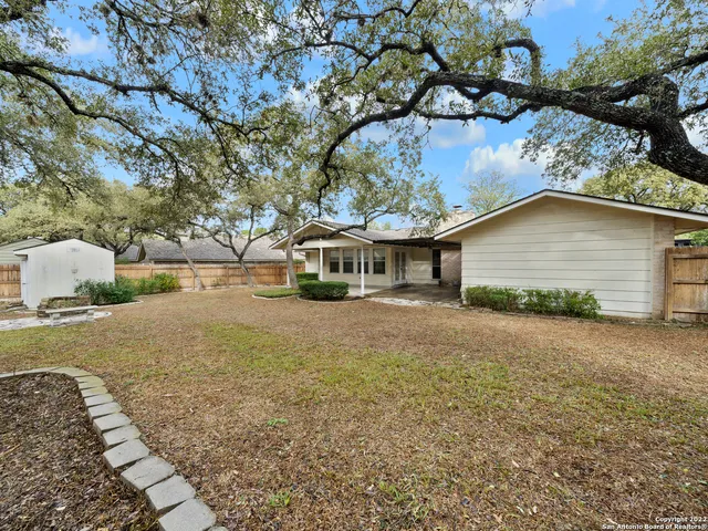 a view of a backyard with table and chairs potted plants and tree