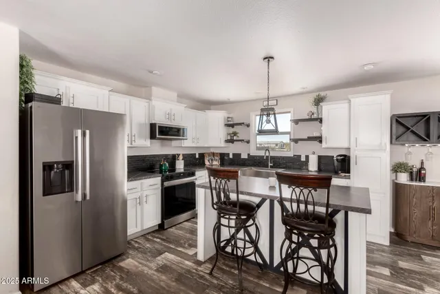 a kitchen with stainless steel appliances granite countertop a sink a stove a refrigerator and cabinets