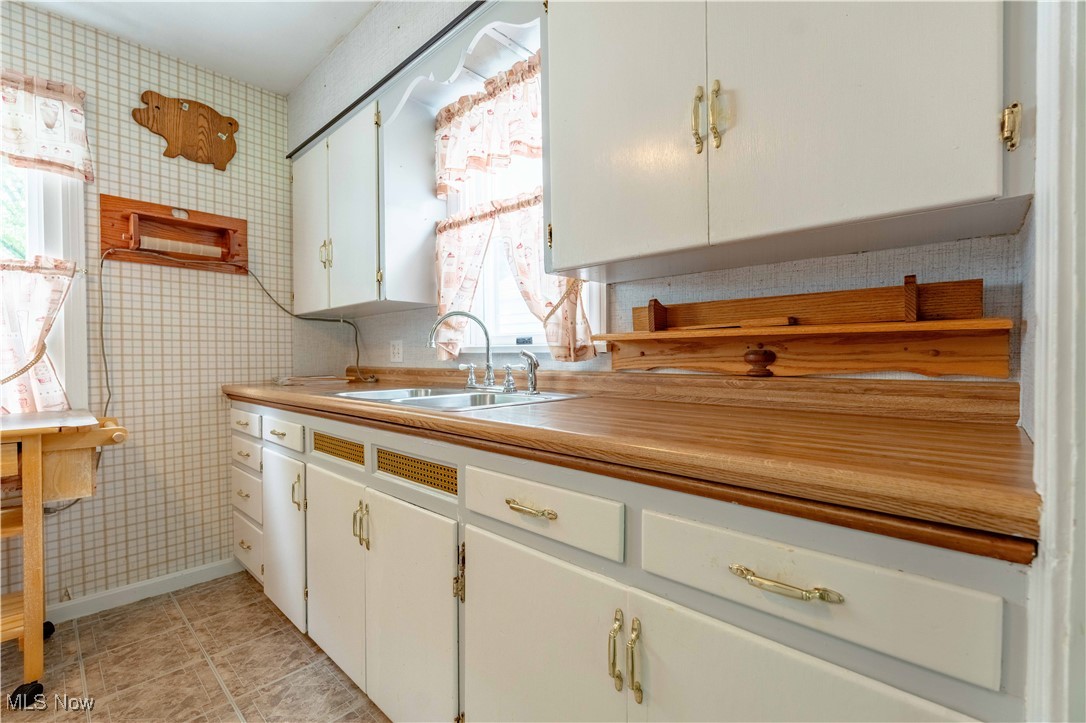 15544 West Calla Road Beloit, OH 44609 - Photo 24 of 40 Kitchen with white cabinets, light countertops, light tile patterned floors, and wallpapered walls