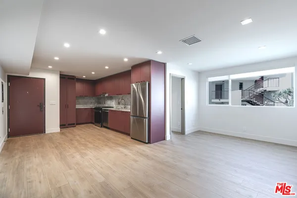 a large kitchen with stainless steel appliances granite countertop a refrigerator and a large window