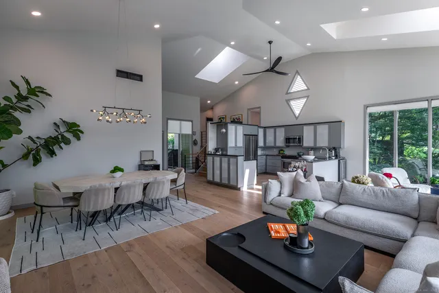 a living room with furniture kitchen view and a large window