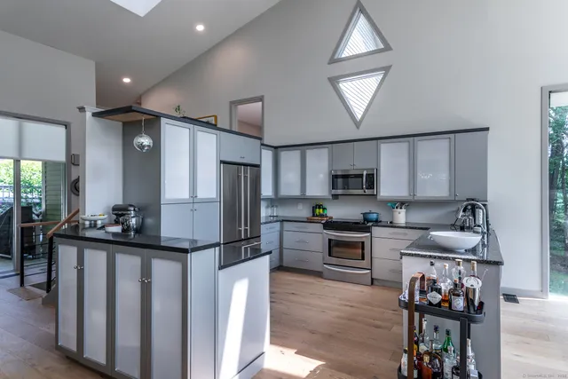 a kitchen with stainless steel appliances granite countertop a refrigerator a stove a sink dishwasher and a refrigerator with wooden floor