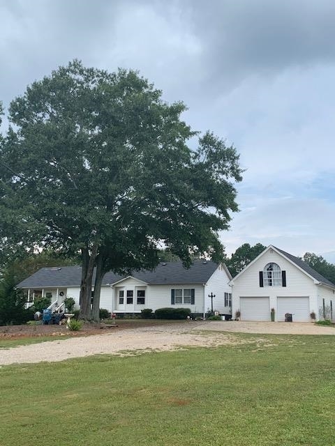 a front view of a house with a garden and trees