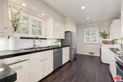 a kitchen with granite countertop a white cabinets sink and stainless steel appliances