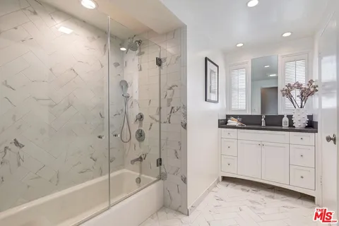 a bathroom with a granite countertop sink a mirror a bathtub and a shower