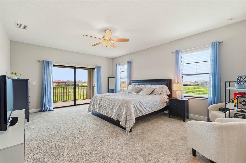 8207 Rushton Place Parrish, FL 34219 - Photo 35 of 65 a spacious bedroom with a bed a chandelier and a flat tv screen