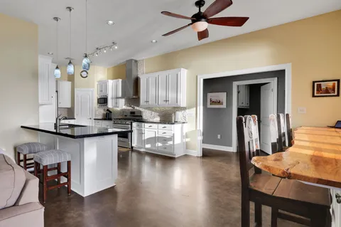 a kitchen with stainless steel appliances kitchen island granite countertop a table chairs in it and wooden floors