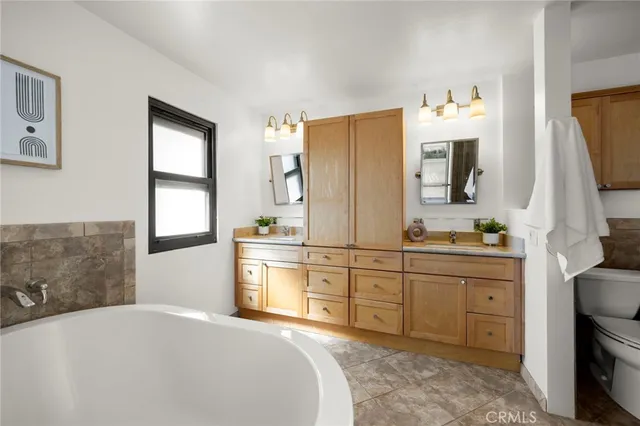 a spacious bathroom with a double vanity sink a mirror a bathtub and window