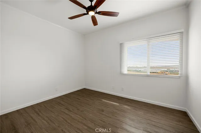 an empty room with wooden floor fan and windows