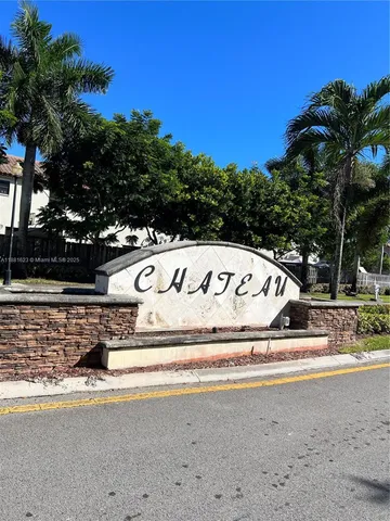 a view of a white house with a yard next to a road