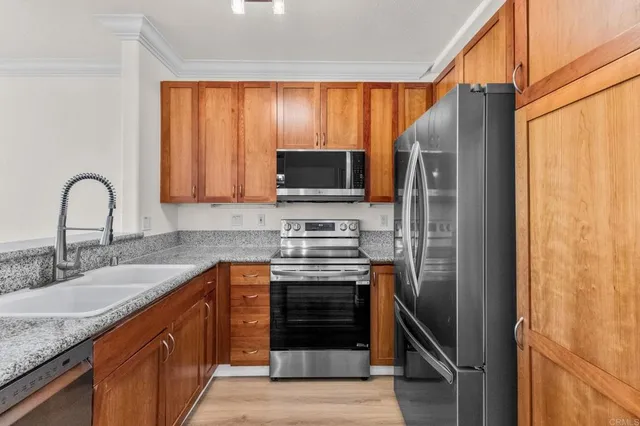 a kitchen with stainless steel appliances granite countertop a stove top oven a sink and a refrigerator