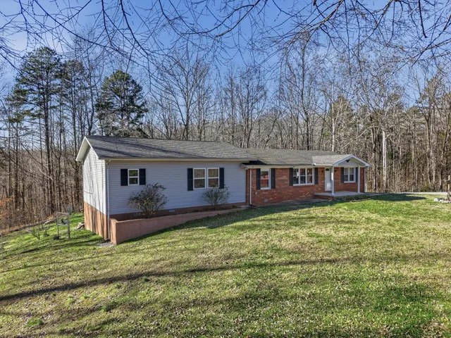 a front view of a house with yard bathtub and trees in the background