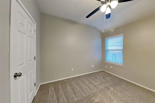 an empty room with a window and a chandelier fan