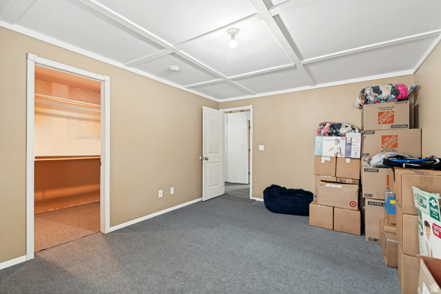 7296 Ridge Road Lake Point, UT 84074 - Photo 37 of 54 Carpeted room featuring a coffered ceiling, neutral wall tones, white trim, and a walk-in closet with shelving and hanging rods