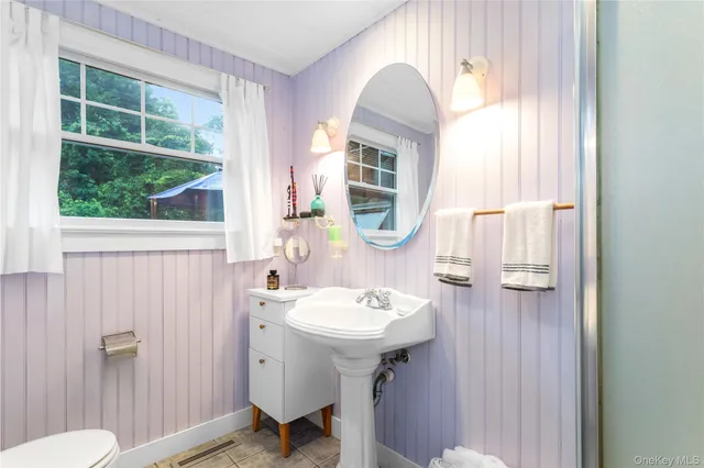 a bathroom with a sink a mirror a toilet and a window