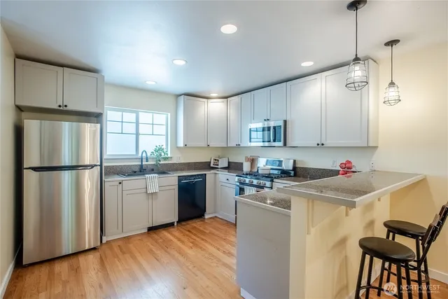 a kitchen with a refrigerator a sink dishwasher and a stove with wooden floor