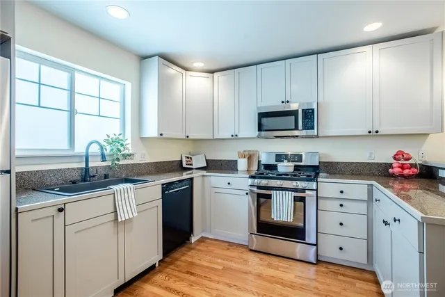 a kitchen with granite countertop white cabinets sink and stainless steel appliances
