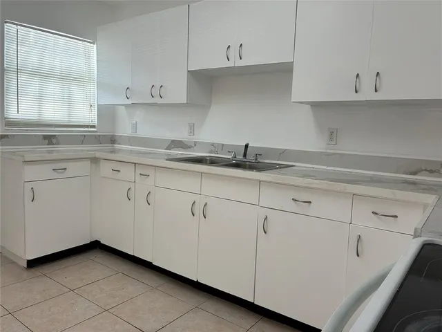 a kitchen with granite countertop white cabinets and a sink