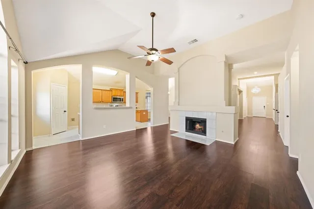 an empty room with wooden floor a chandelier fan a fireplace and wooden floor