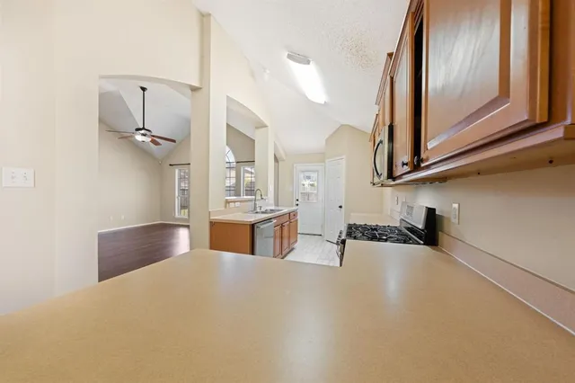 a kitchen with stainless steel appliances a refrigerator a sink a oven and white cabinets