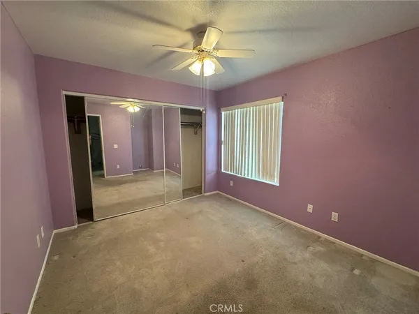 an empty room with windows and fan