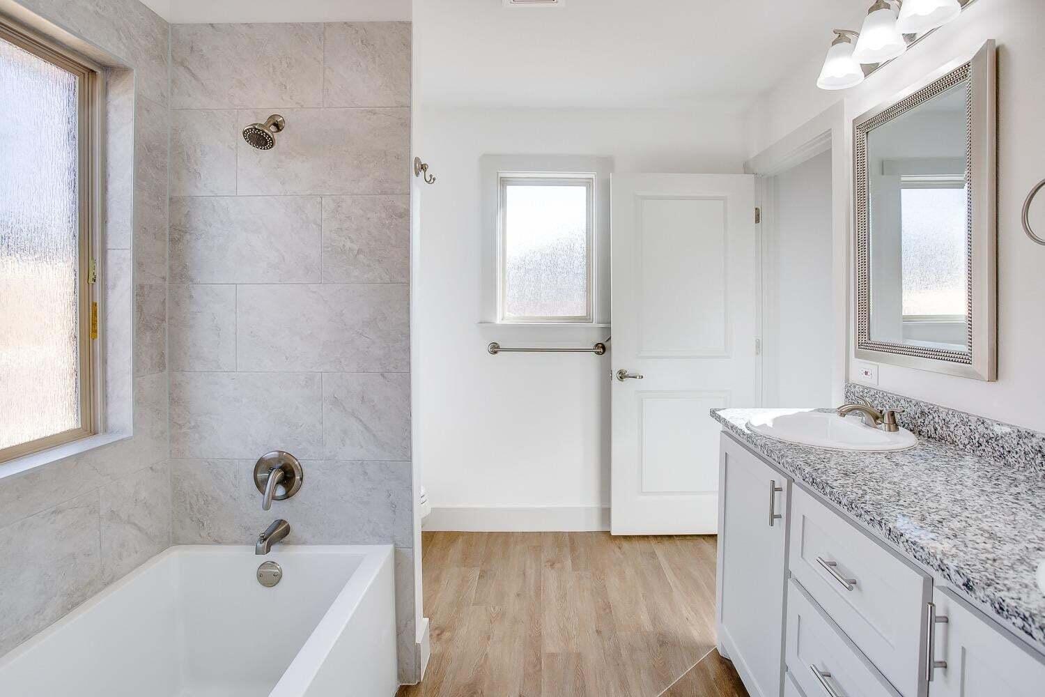 811 North 4th Street Wolfforth, TX 79382 - Photo 13 of 18 a bathroom with a granite countertop sink a mirror and a bathtub
