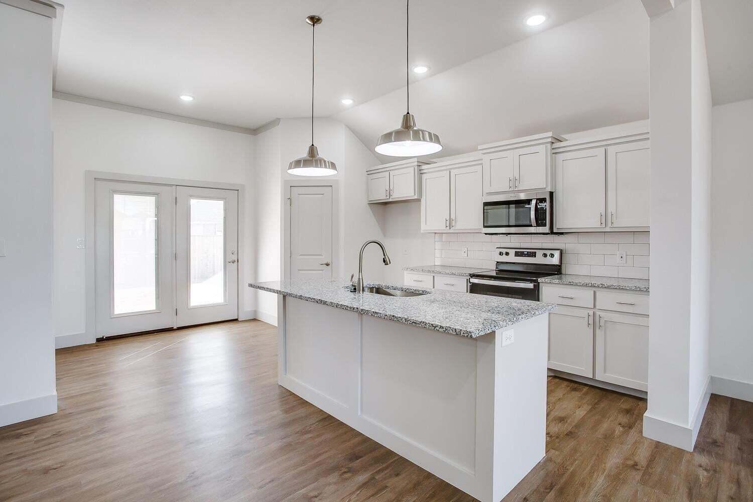 811 North 4th Street Wolfforth, TX 79382 - Photo 4 of 18 a kitchen with stainless steel appliances kitchen island granite countertop a sink a stove and cabinets