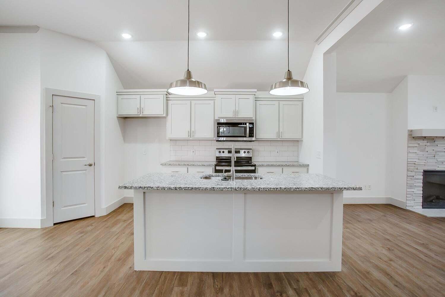 811 North 4th Street Wolfforth, TX 79382 - Photo 5 of 18 a large kitchen with stainless steel appliances granite countertop a sink a stove and a wooden floors