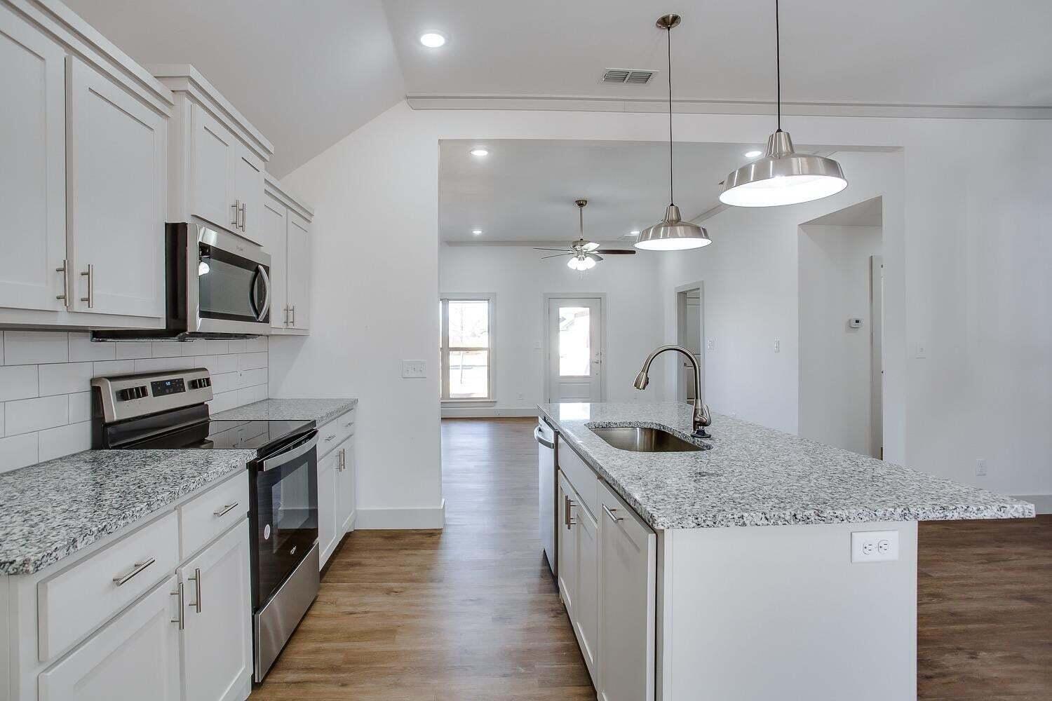 811 North 4th Street Wolfforth, TX 79382 - Photo 7 of 18 a kitchen with stainless steel appliances granite countertop a sink a stove and a wooden floors