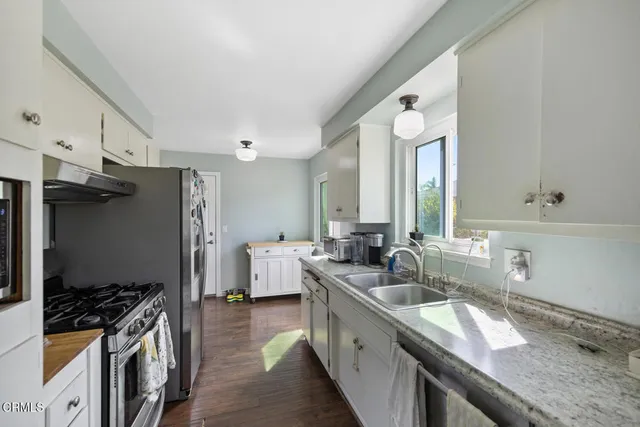 a kitchen with granite countertop a sink stove and refrigerator