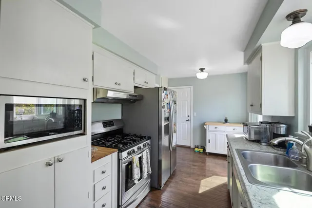 a kitchen with stainless steel appliances a stove a sink a microwave a refrigerator and cabinets